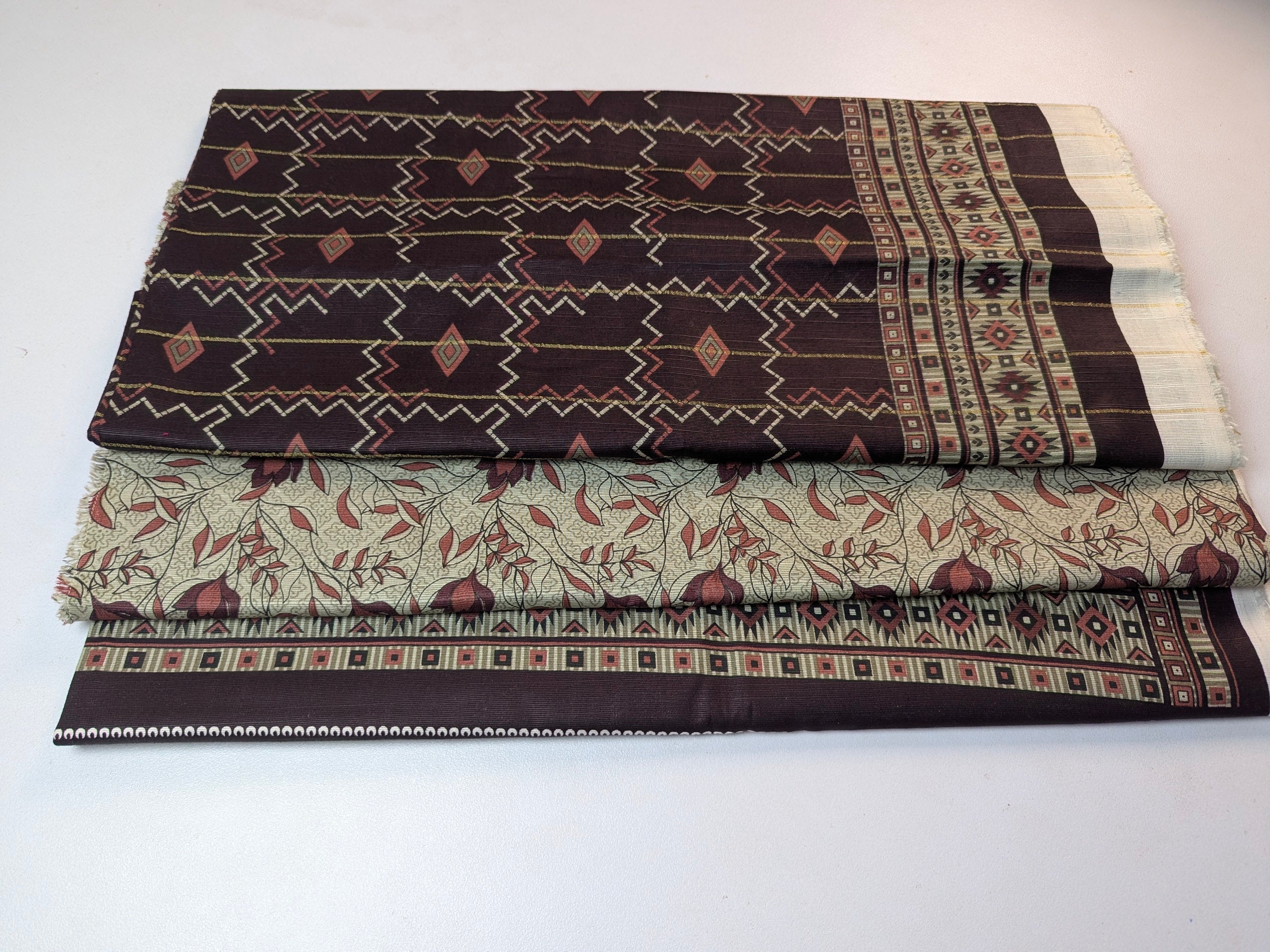 Two folded fabrics with intricate patterns on a white background