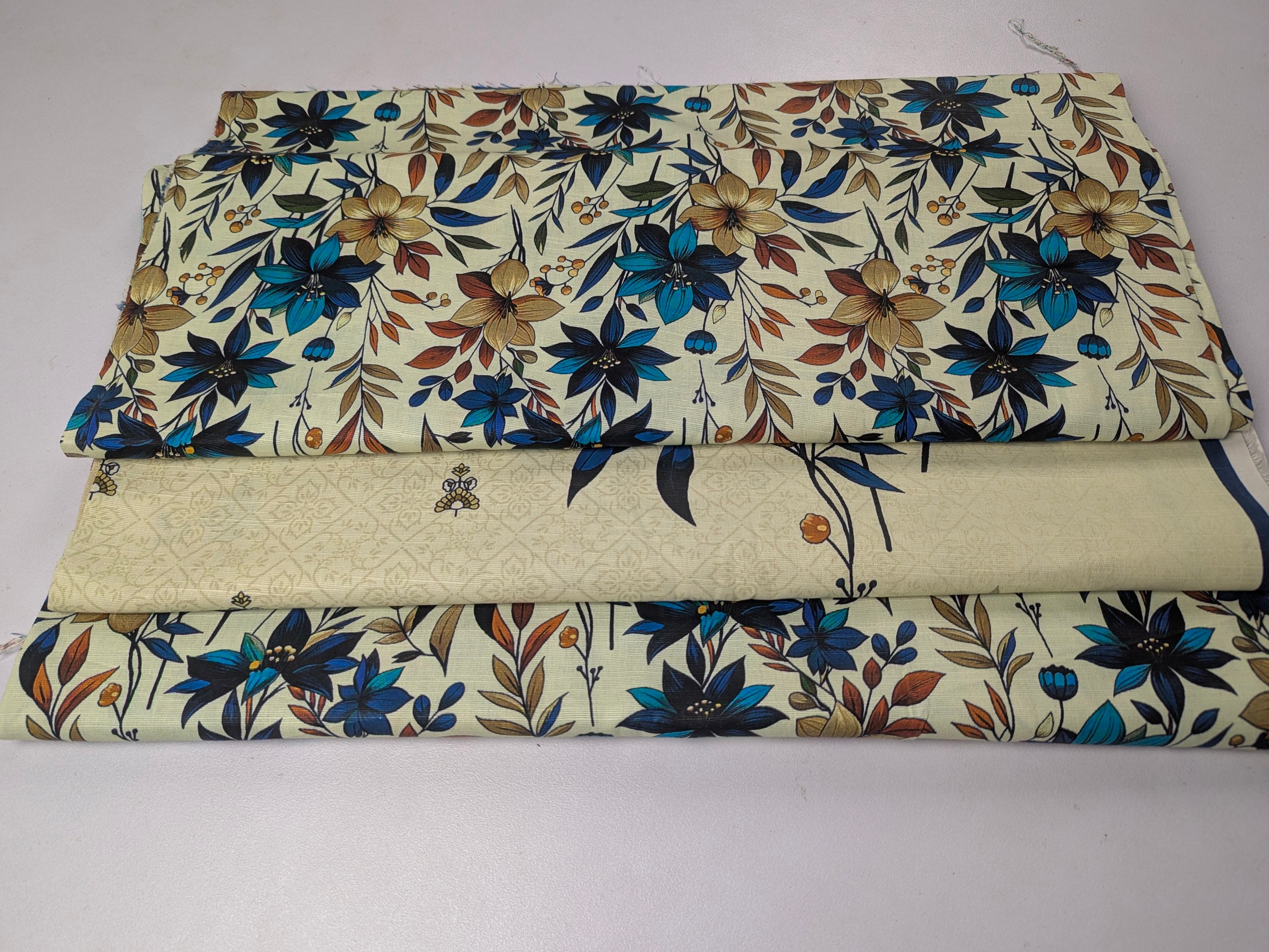 Rolls of floral fabric with blue, brown, and beige flowers on a white background