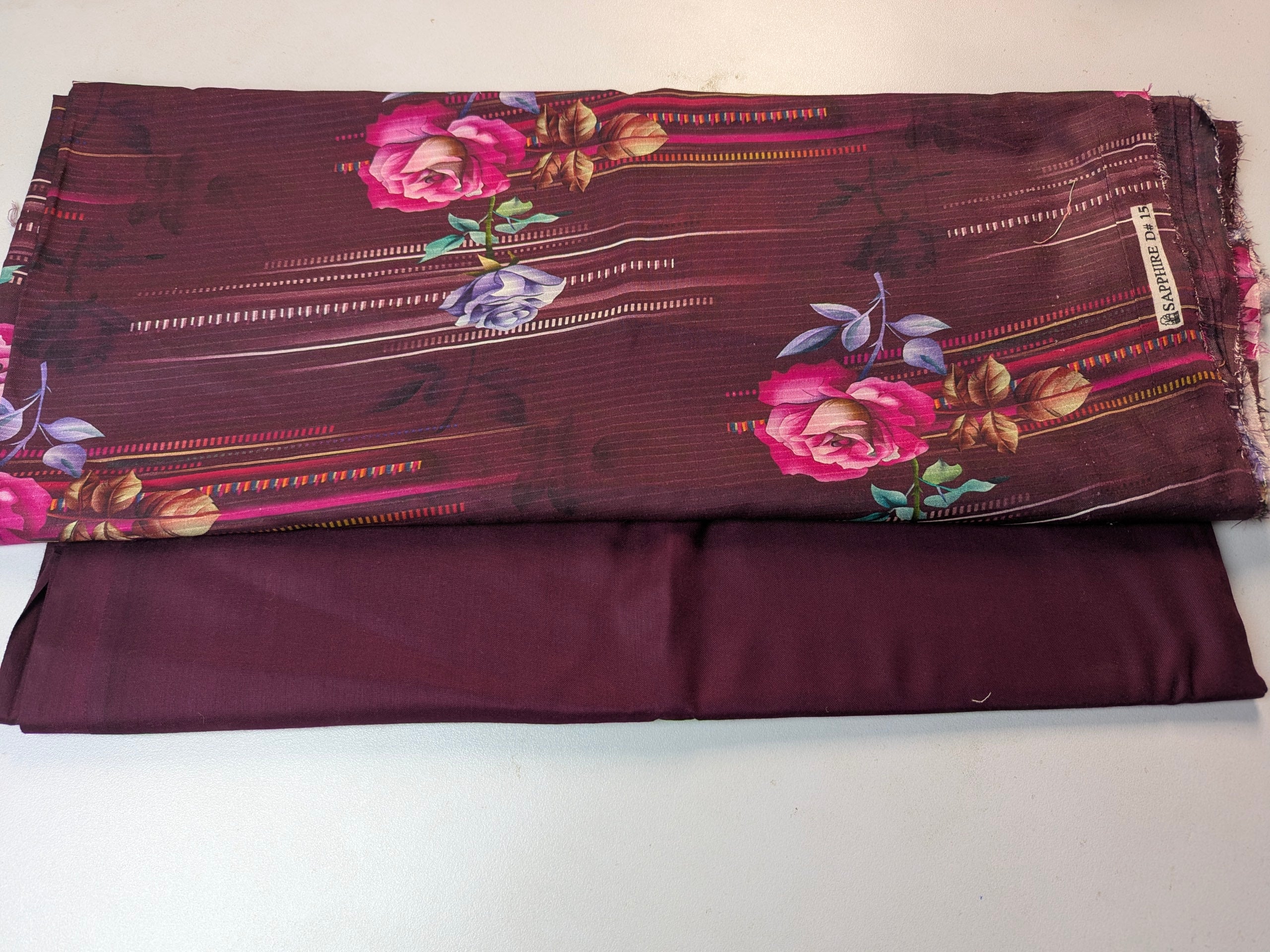 Two pieces of fabric, one plain and one with floral pattern, on a white background.