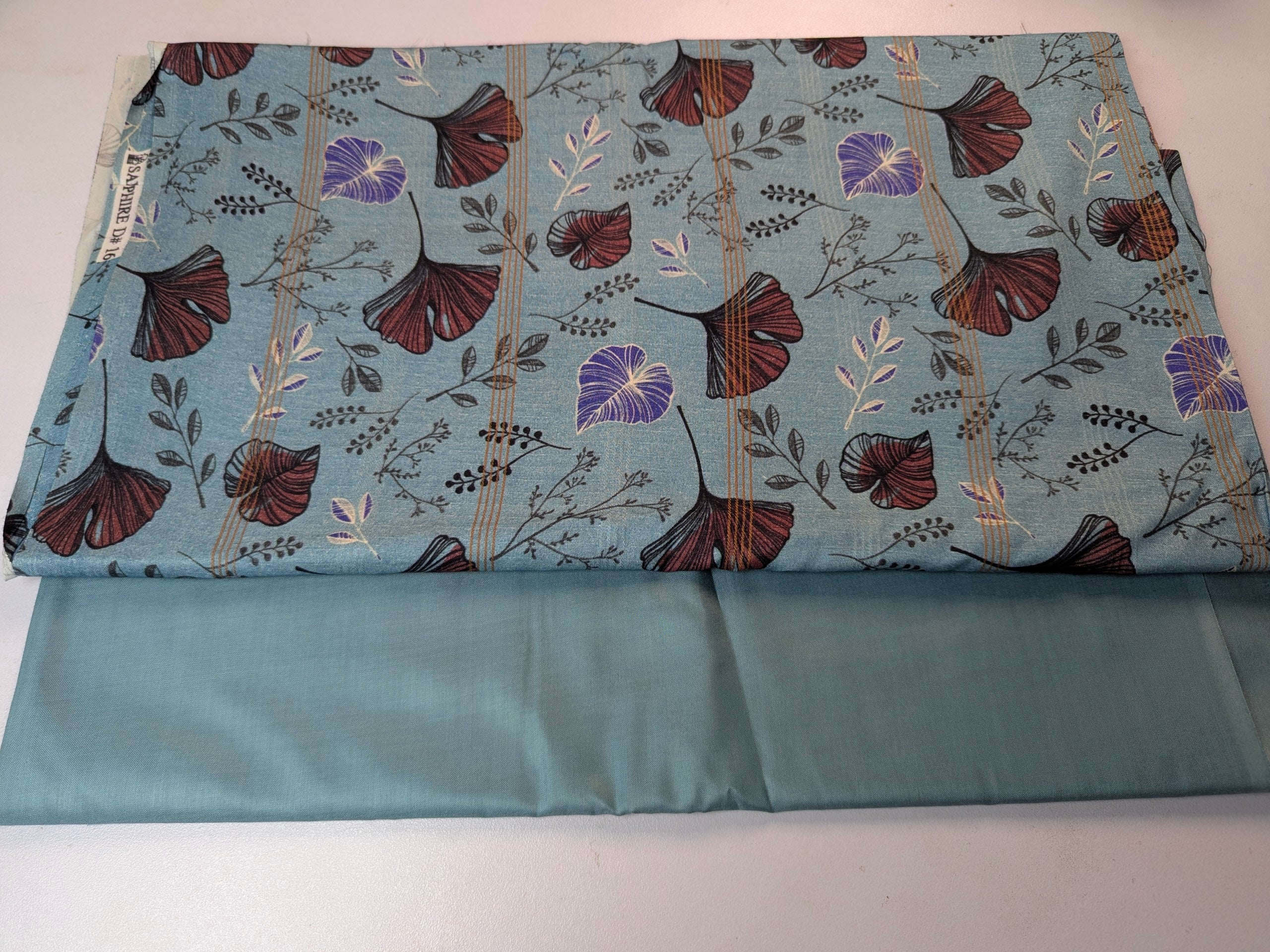 Floral-patterned fabric with a plain blue lining on a white background