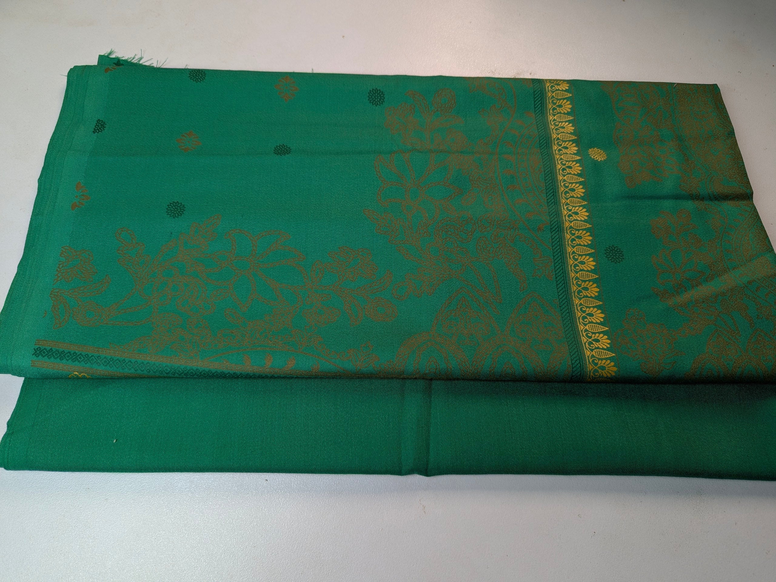 Green fabric with gold patterns on a white background